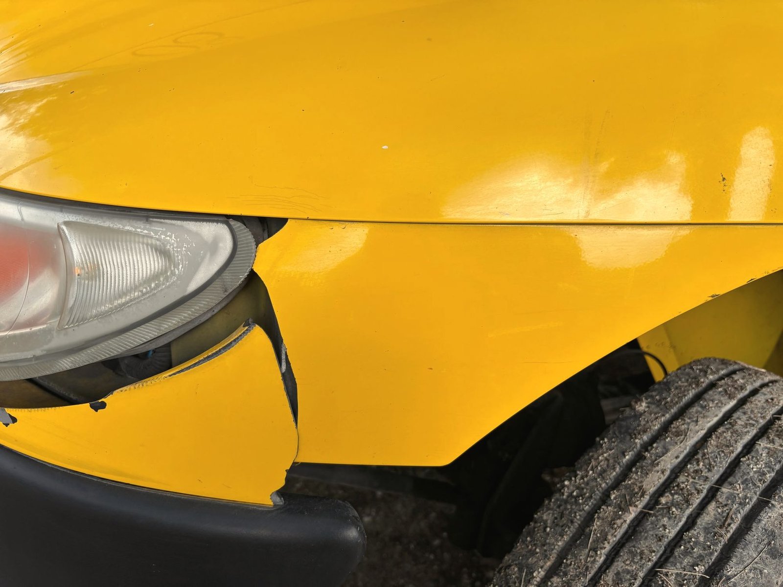 A yellow front fender pushed back and split where it meets the headlight